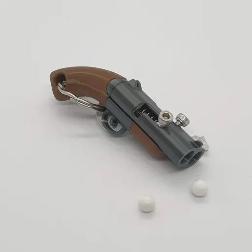 Mini Llavero Pistola de Muelle Funcional - Dispara Bolas de Plástico